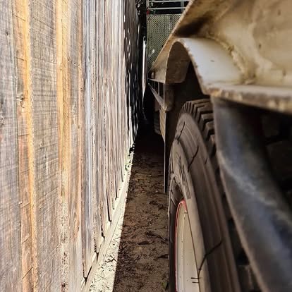 Small Mountain Timbers truck navigating a tight side access between fences